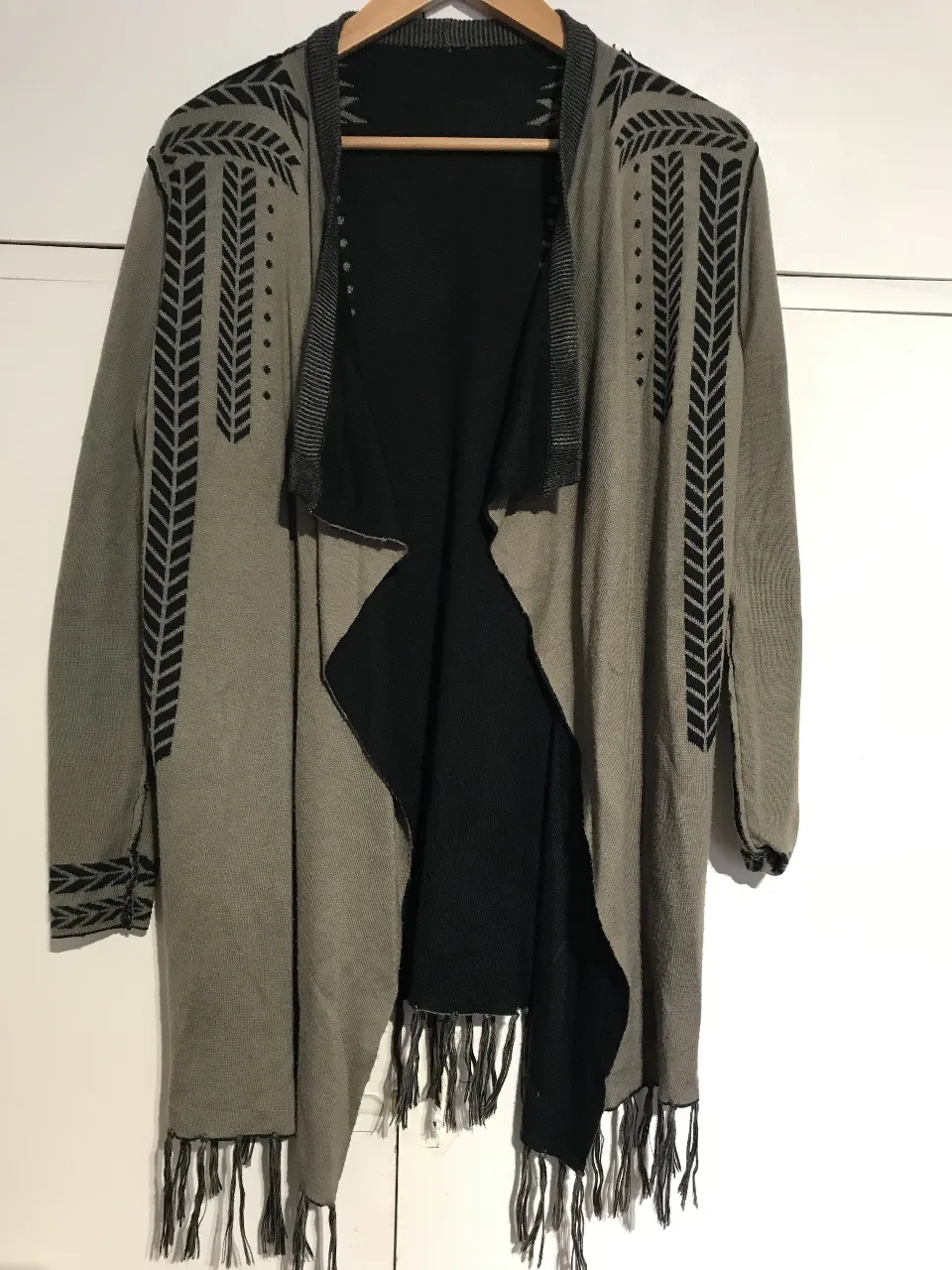 Cardigan largo con flecos en el bajo. Diseño con detalles geométricos en negro y gris. Se puede usar de ambos lados.Ideal para un look bohemio y casual.