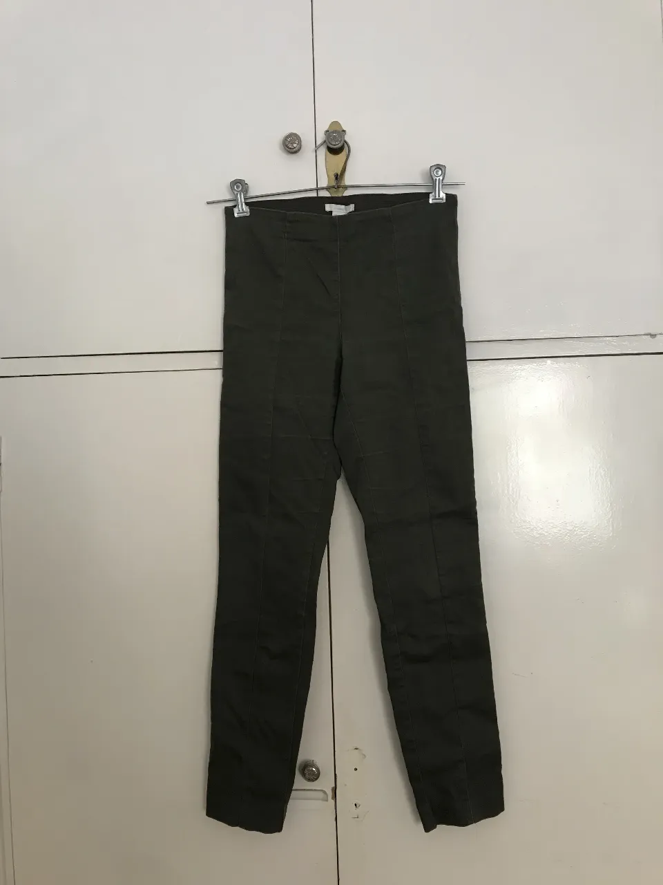 Pantalón chupín de mujer, tiro alto, color verde oscuro, con detalles de costura en la parte delantera y trasera. Talle 6. 