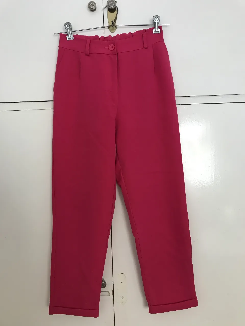 Pantalón sastrero de color fucsia, tiro alto, con pinzas y bolsillos delanteros. Ideal para un look elegante y moderno. Tiene detalles en uno de los lados ( hilos sueltos y pelotitas)