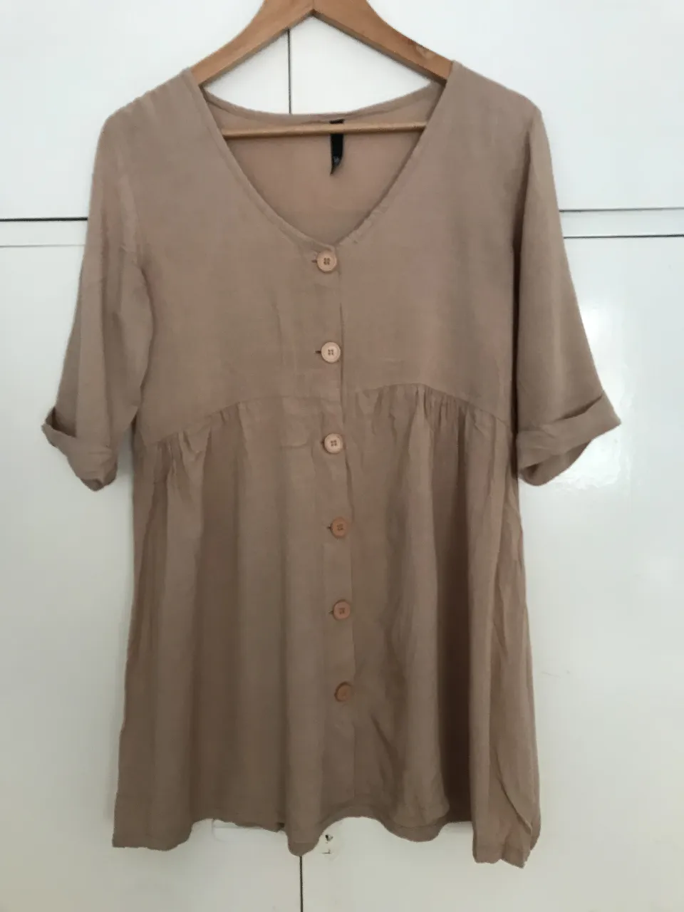 Vestido  beige con botones frontales y mangas cortas. Ideal para un look casual y fresco.