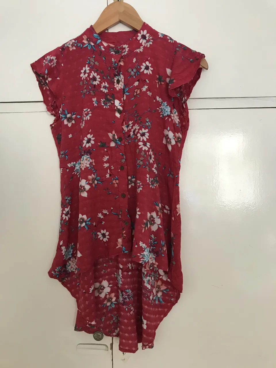 Blusa roja/fucsia con estampado floral, cuello alto y corte asimétrico, con cola larga Ideal para un look casual y femenino.