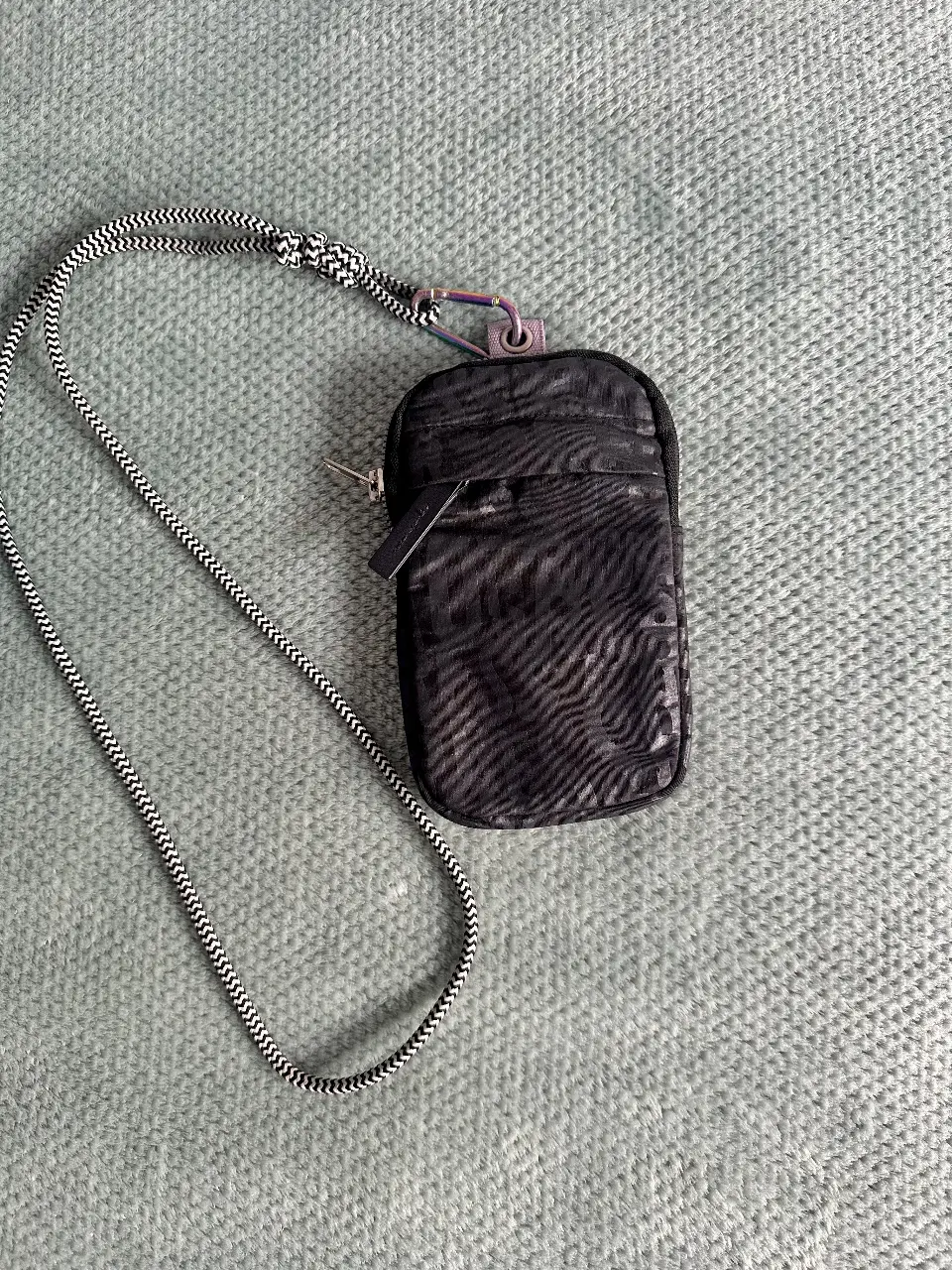 Portacelular  negro con correa ajustable y cierre. Ideal para llevar lo esencial con estilo. 