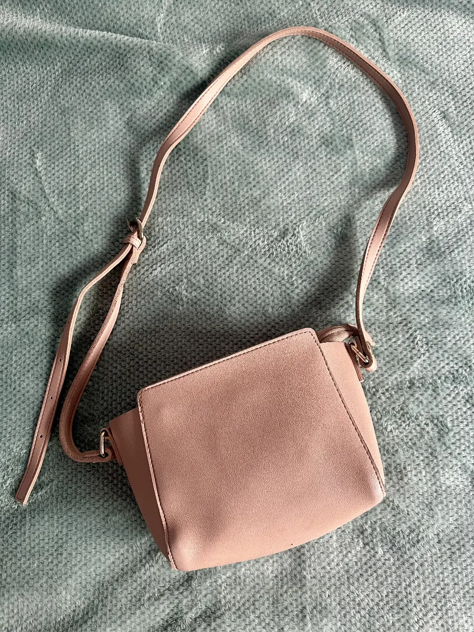 Cartera bandolera de color rosa, con cierre y correa ajustable. Ideal para llevar tus esenciales con estilo.
