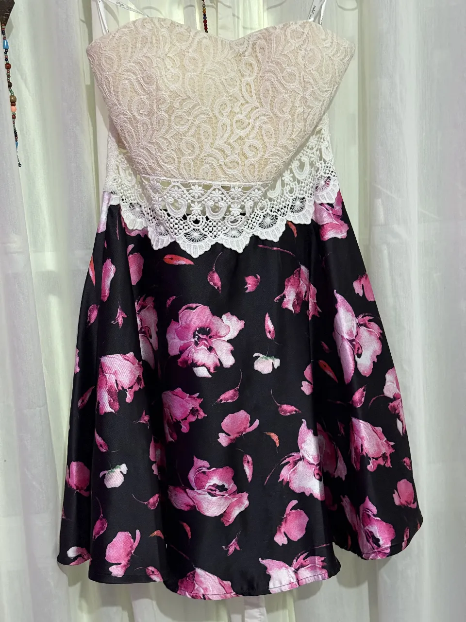 Vestido mini de fiesta para mujer, con corpiño de encaje blanco y falda con estampado floral en tonos rosas sobre fondo negro. Ideal para eventos especiales.