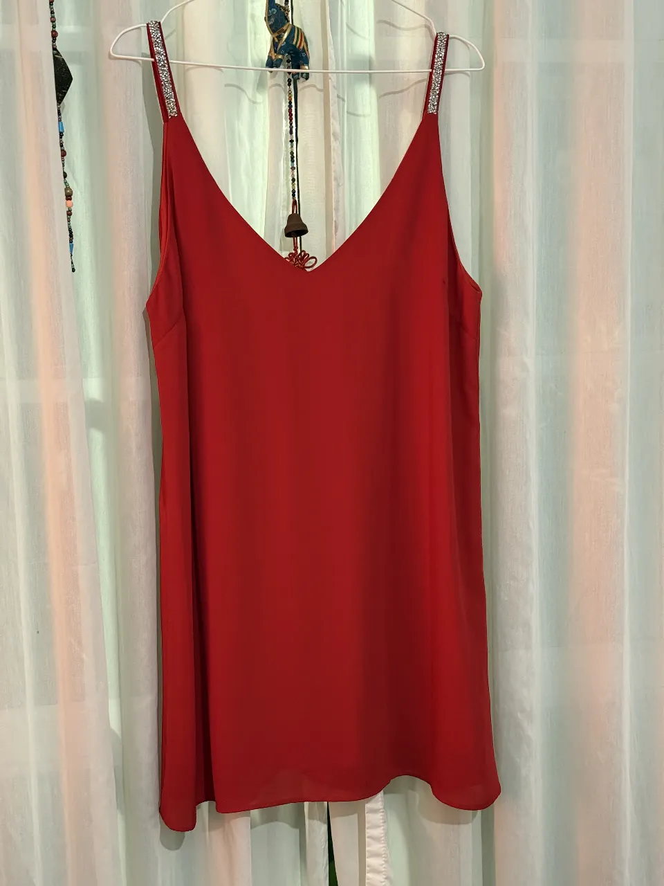 Vestido mini rojo con tiras finas adornadas con brillos. Ideal para fiestas y eventos especiales. Diseño elegante y femenino.