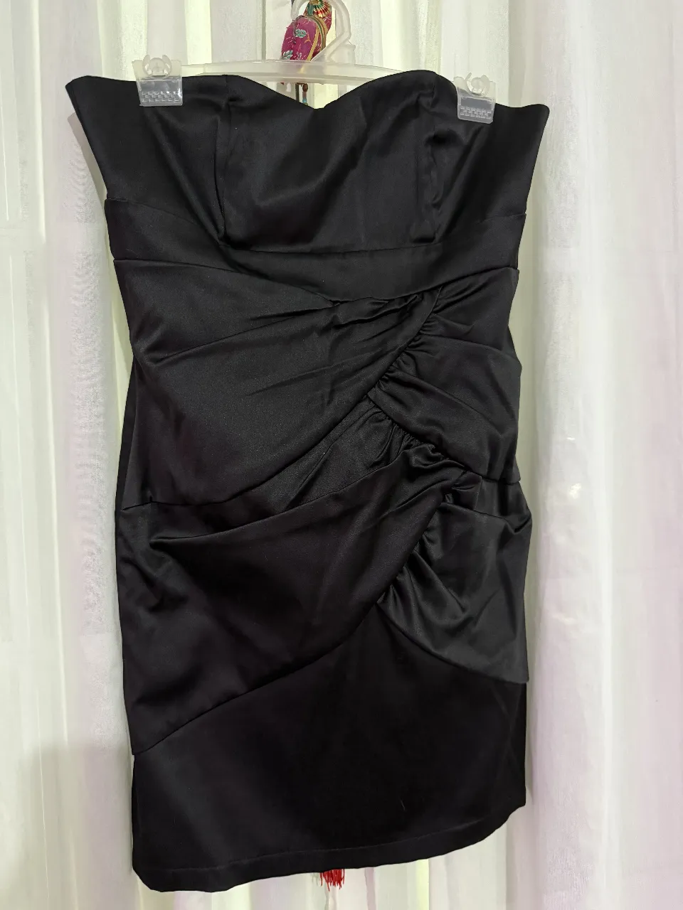 Vestido strapless negro, con frunces en la parte delantera y un diseño elegante. Ideal para fiestas y eventos especiales.