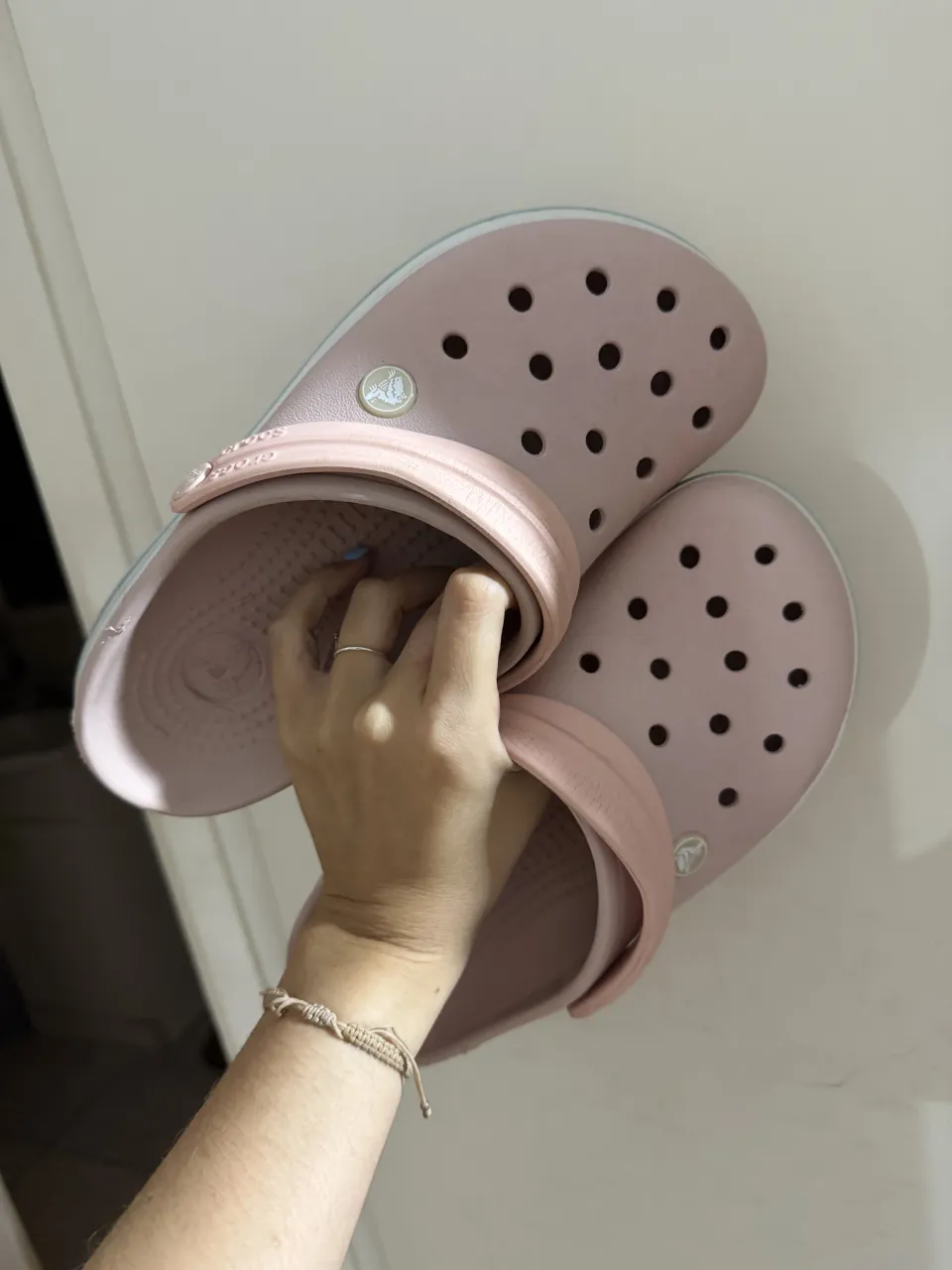 Ojotas color rosa pálido con detalles en blanco y celeste en la suela. Tienen el logo de la marca en relieve.