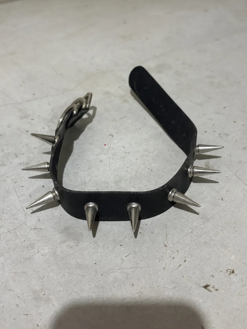 Collar choker de cuero negro con tachas plateadas en forma de púa. Tiene hebilla para ajustar y es perfecto para un look rocker o alternativo.