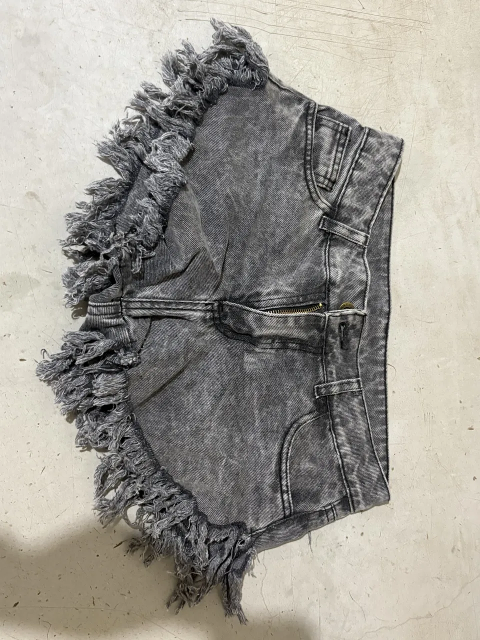 Shorts de jean tiro bajo con roturas y flecos. Lavado gris desgastado, súper cancheros y modernos. Ideales para un look relajado y con onda.