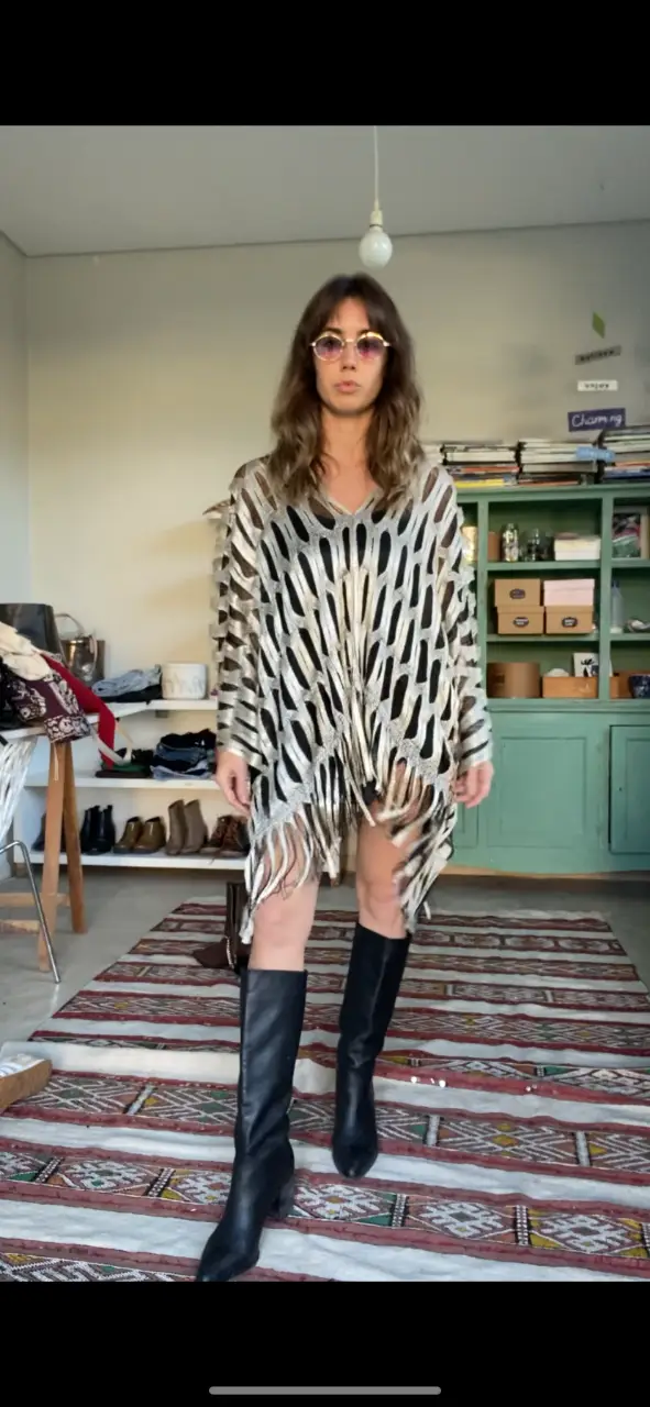 Vestido mini con diseño calado en blanco y dorado, con flecos en el borde inferior. Ideal para un look bohemio y festivo.