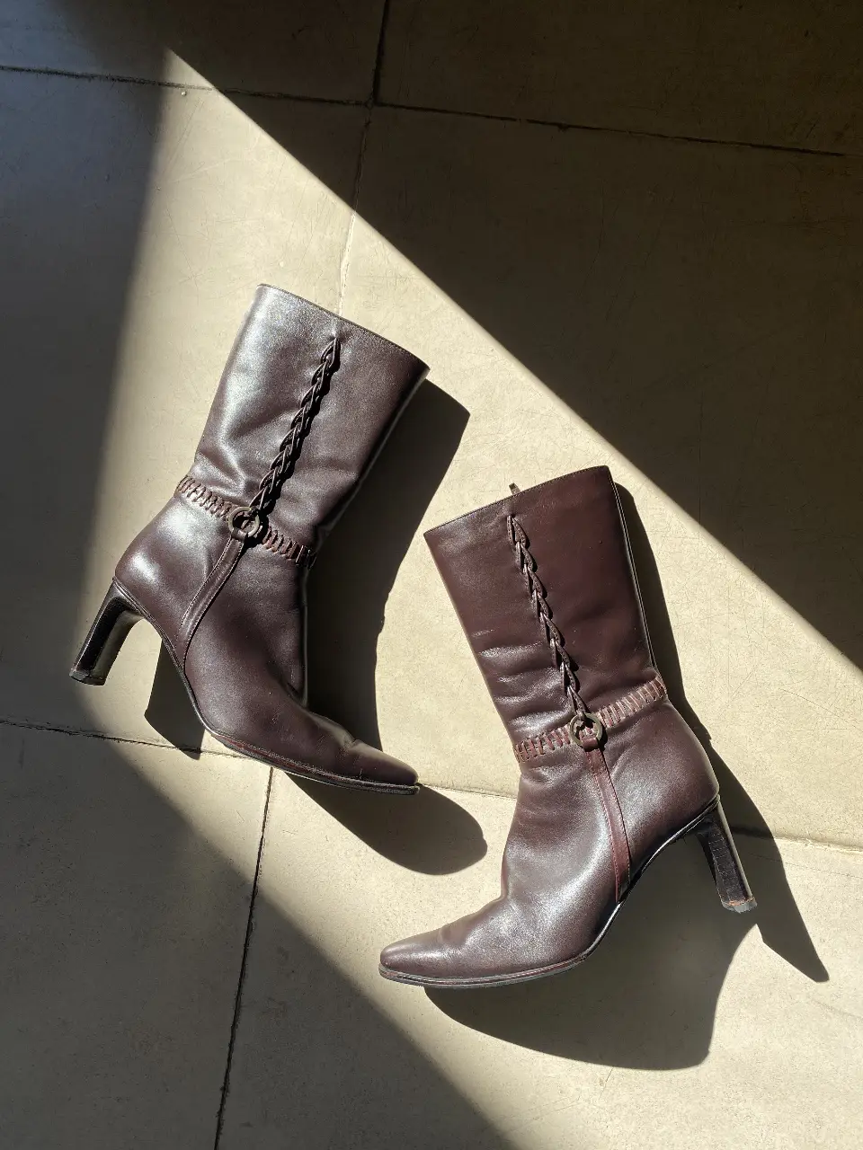 Botas de caña alta de cuero marrón con detalles trenzados y cierre lateral. Ideales para un look elegante y sofisticado.