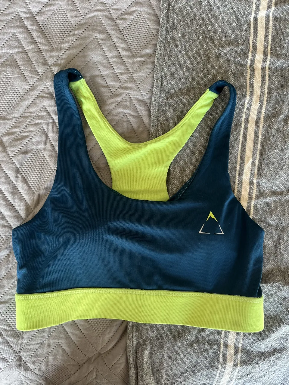 Top deportivo de mujer, con diseño en color azul y detalles en verde lima. Ideal para actividades de fitness y entrenamiento. Cuenta con un logo triangular en la parte delantera y la marca K-SPORT.
