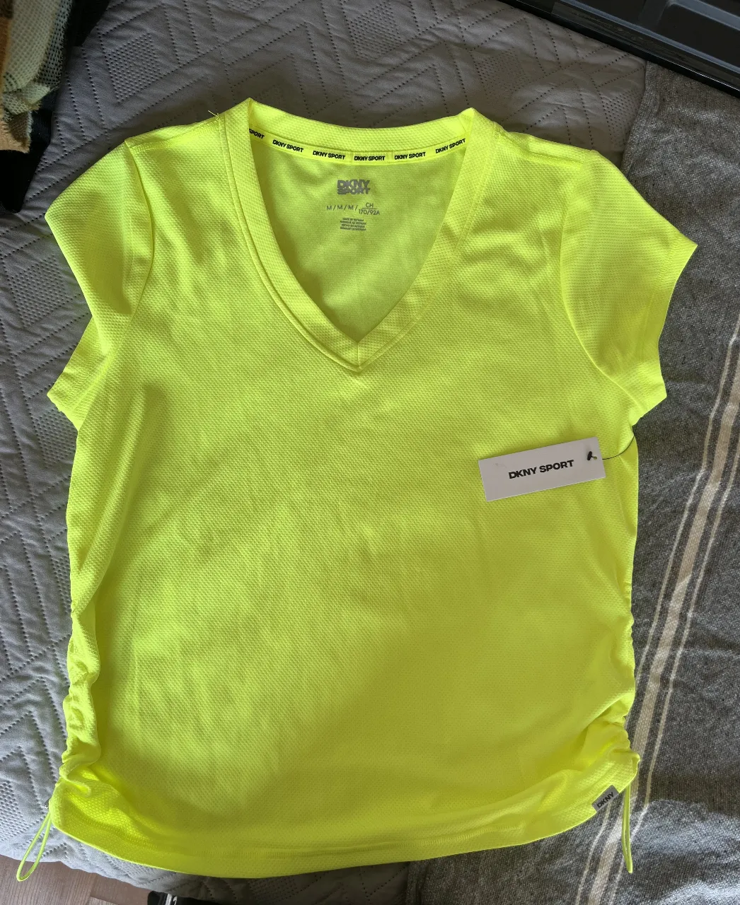 Remera deportiva DKNY Sport de mujer, color amarillo flúo, con ajuste en los laterales. Ideal para entrenar.