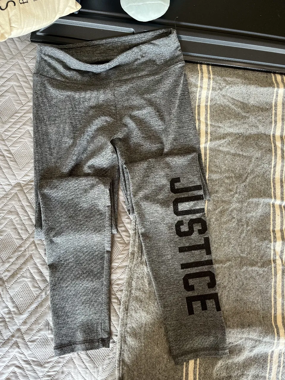 Calzas deportivas grises de la marca Justice, con la palabra "JUSTICE" estampada en negro en la pierna. Ideales para actividades físicas o para un look casual y cómodo.