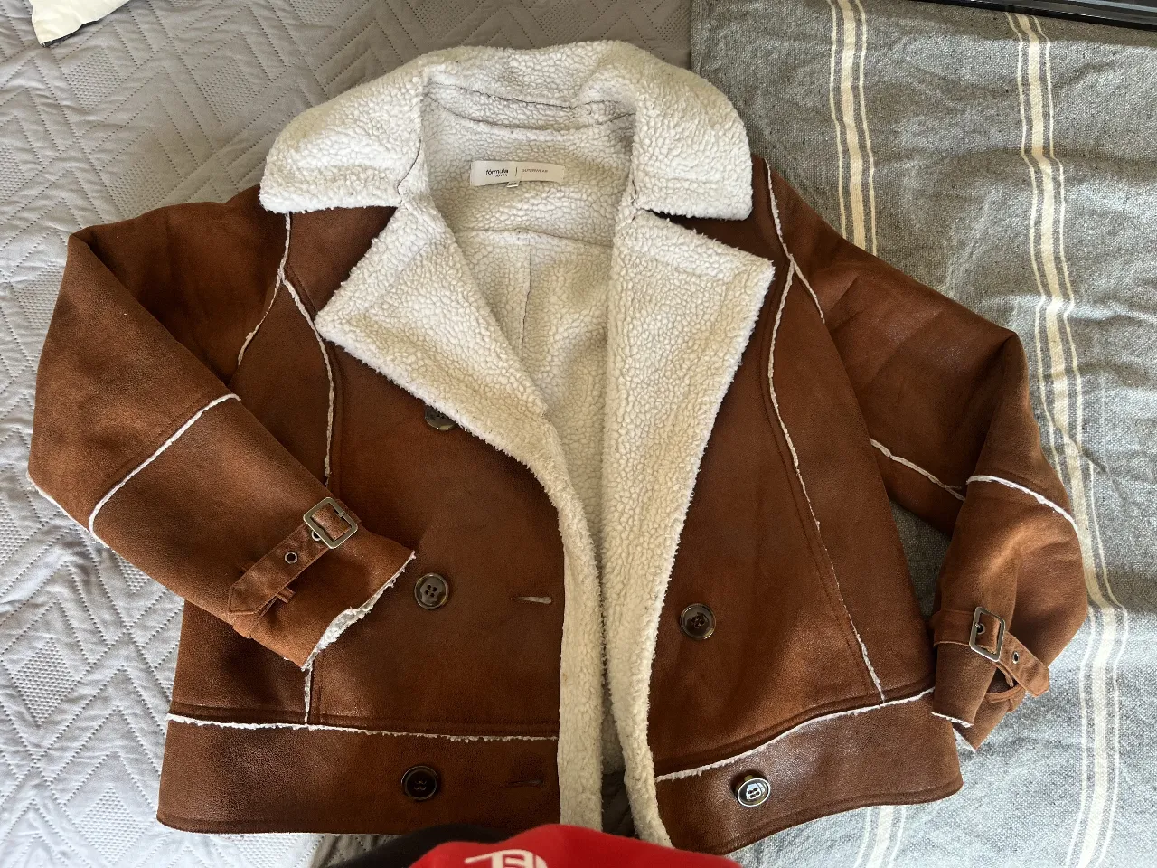 Campera gamulan de mujer, marrón con interior y detalles en blanco. Estilo aviador, con detalles de hebillas en las mangas y botones. Ideal para el invierno.