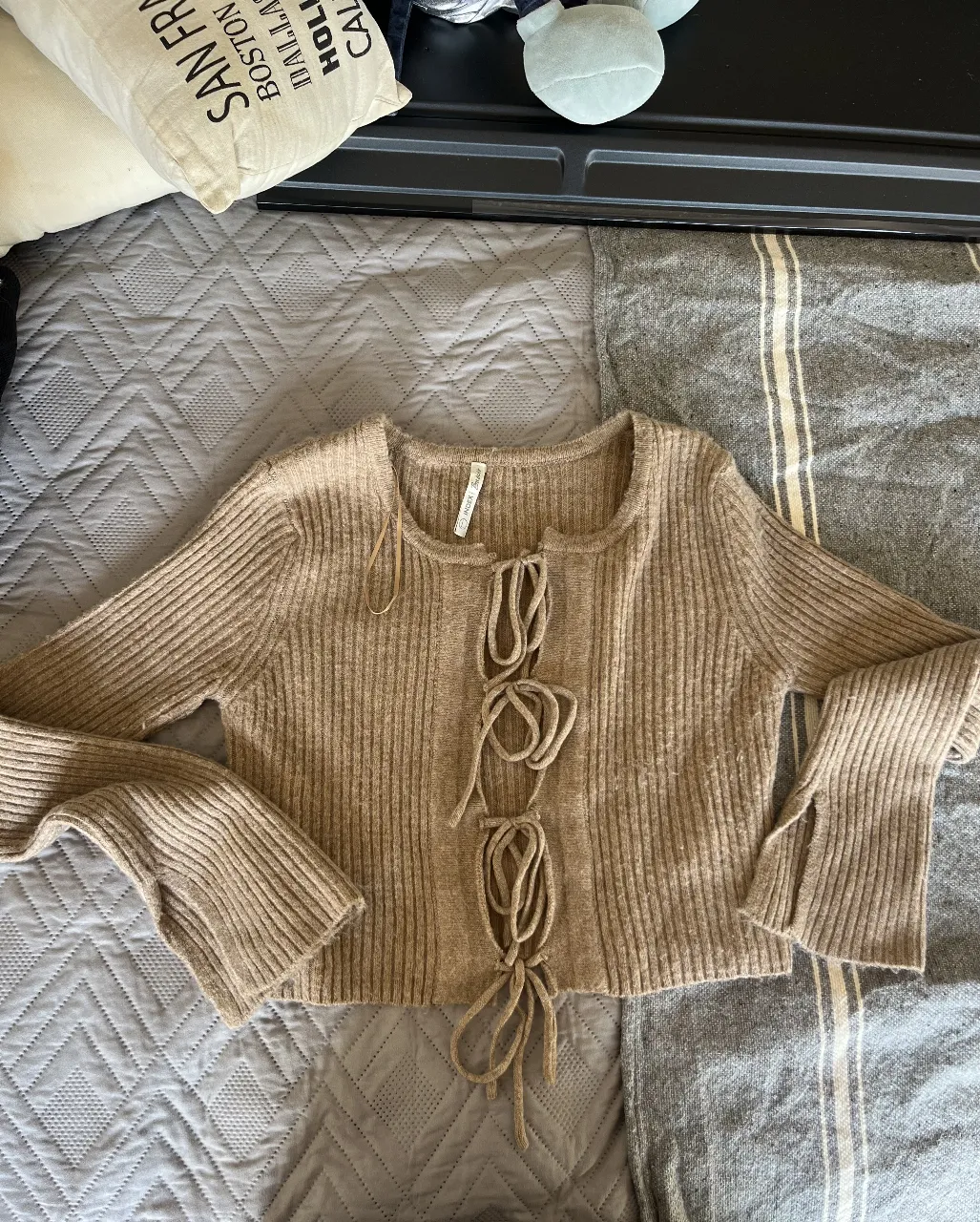 Sweater largo de punto con detalle de lazada en el frente. Mangas largas con abertura en los puños. Ideal para un look casual y cómodo.