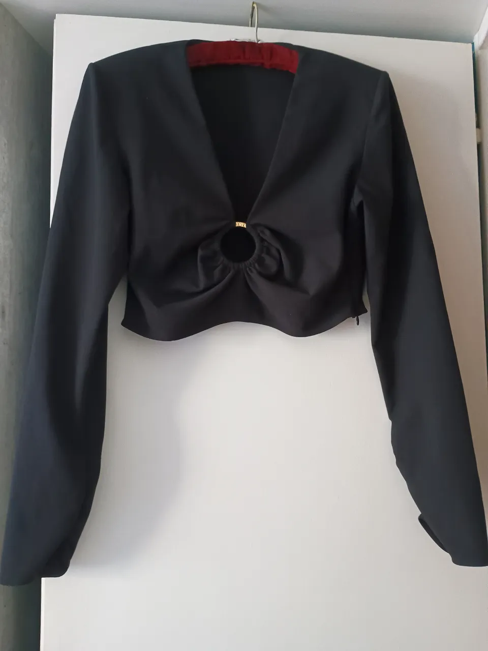 Blusa negra de manga larga con detalle de abertura y aro en el centro. Ideal para un look elegante y sofisticado.