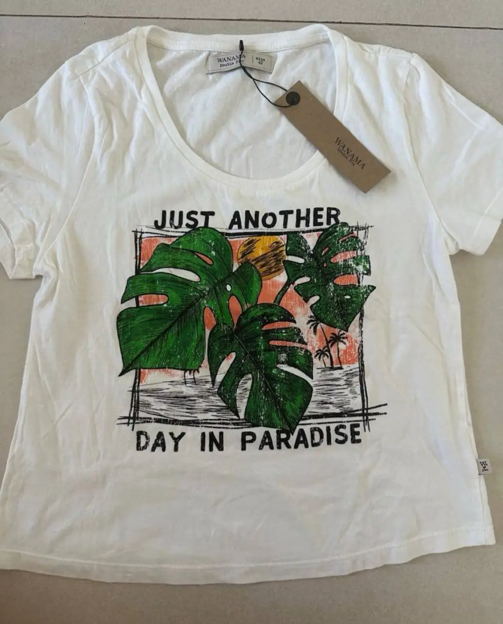Remera Wanama de mujer blanca con estampado de hojas tropicales. Talle M. Ideal para un look casual y fresco.