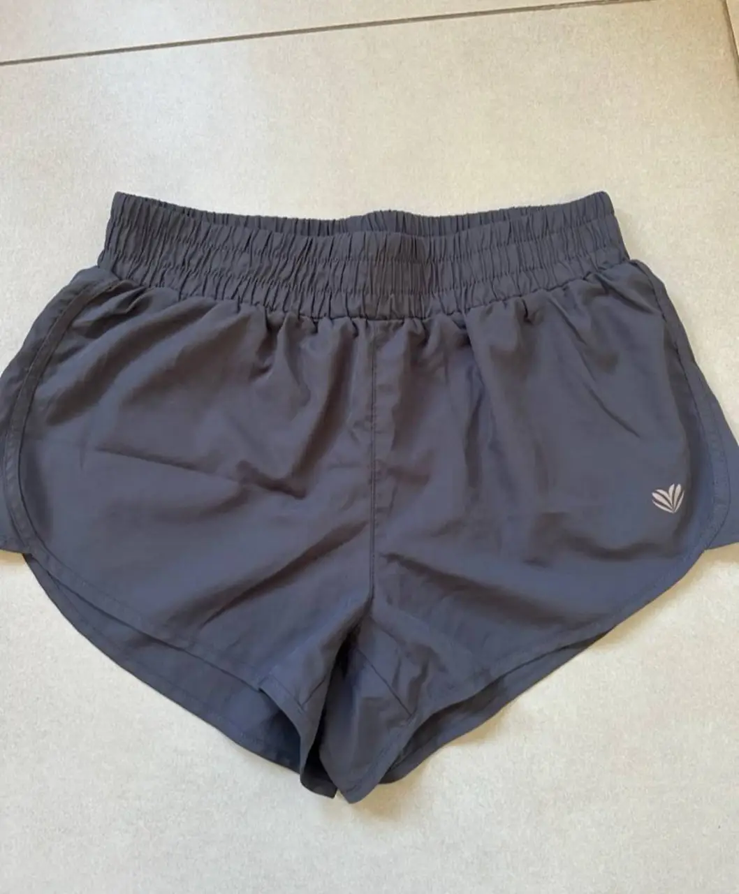 Short deportivo gris de mujer, ideal para actividades físicas. Con cintura elastizada y un pequeño bolsillo trasero con cierre. Marca Forever 21, talle S.