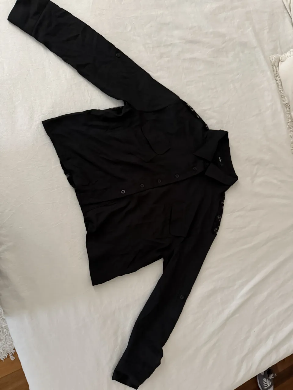 Camisa negra de manga larga con detalles de encaje en la espalda y un corte abierto. Ideal para un look canchero y con un toque de sensualidad.