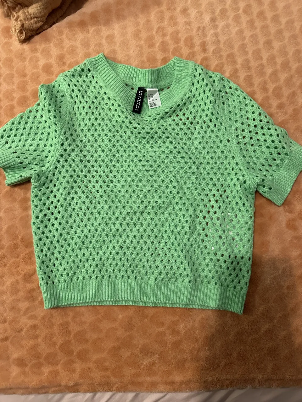 Remera verde de tejido de red con mangas cortas y cuello redondo.