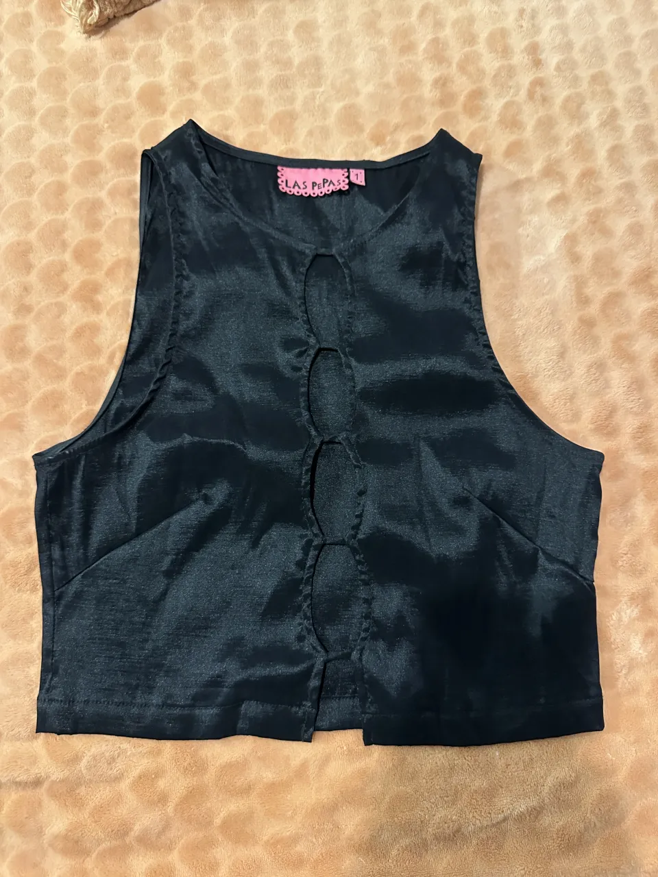 Top negro sin mangas con escote redondo y detalle de recortes frontales con botones.