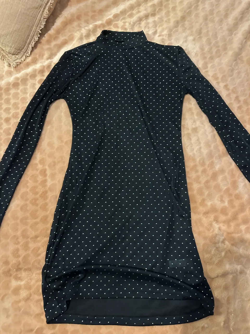 Vestido negro con lunares blancos y cuello alto.