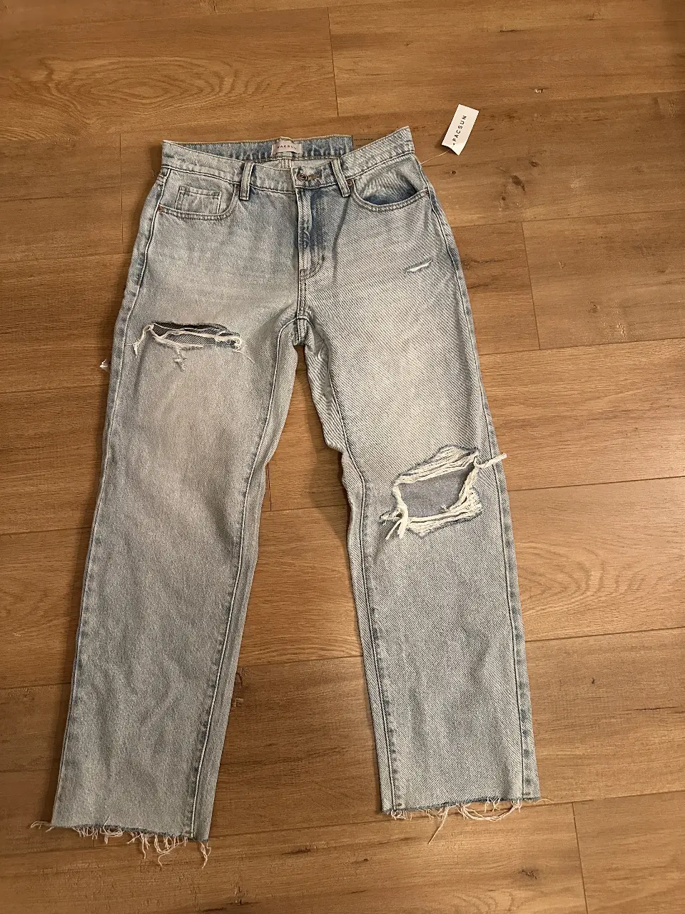 Jeans rectos de mujer, tiro medio, con roturas en las rodillas. Talle 26. Ideal para un look casual y moderno.