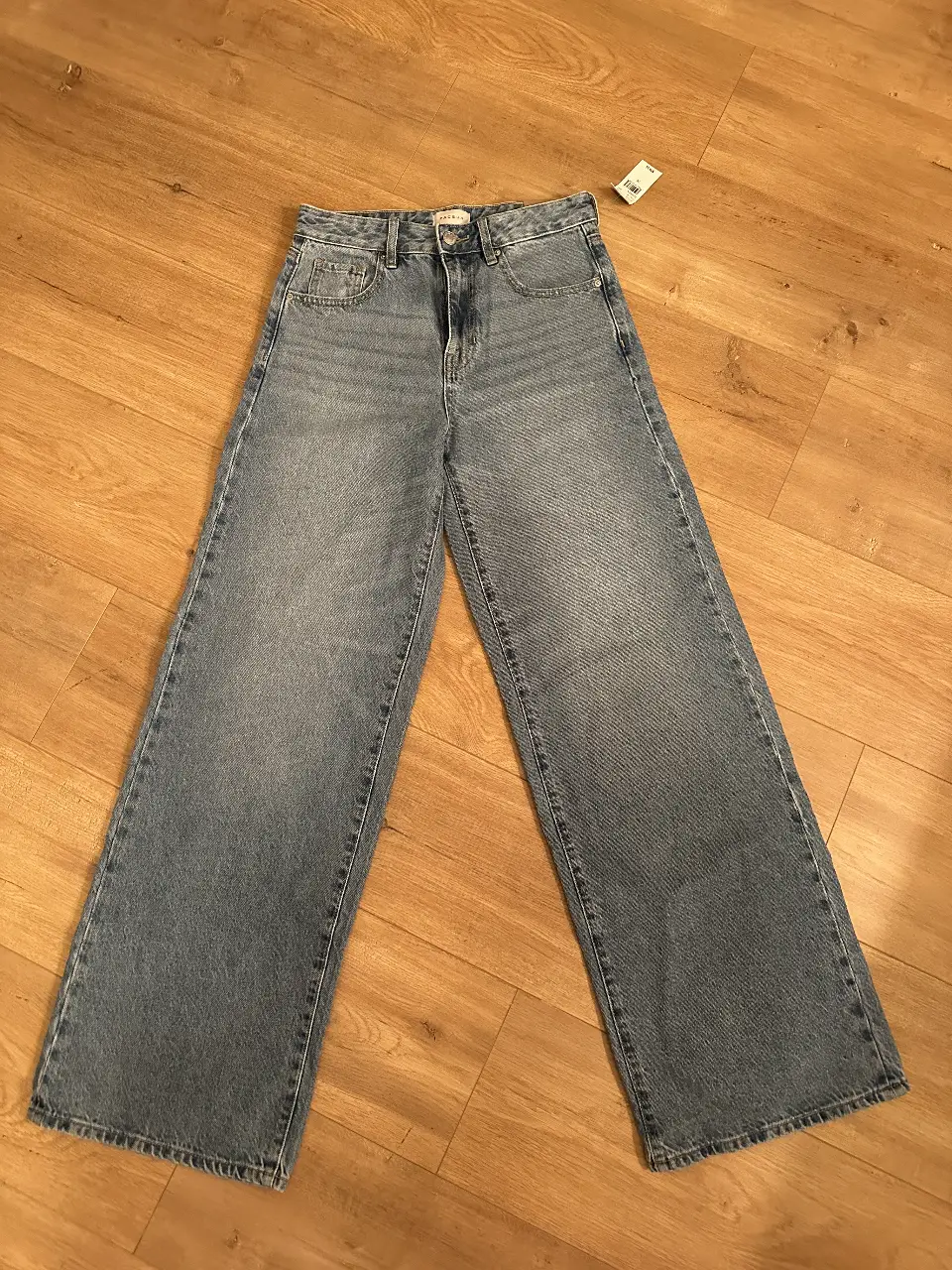 Jeans de mujer, tiro alto, corte recto y ancho, color azul claro, con etiqueta de la marca Pacsun, talle 26.