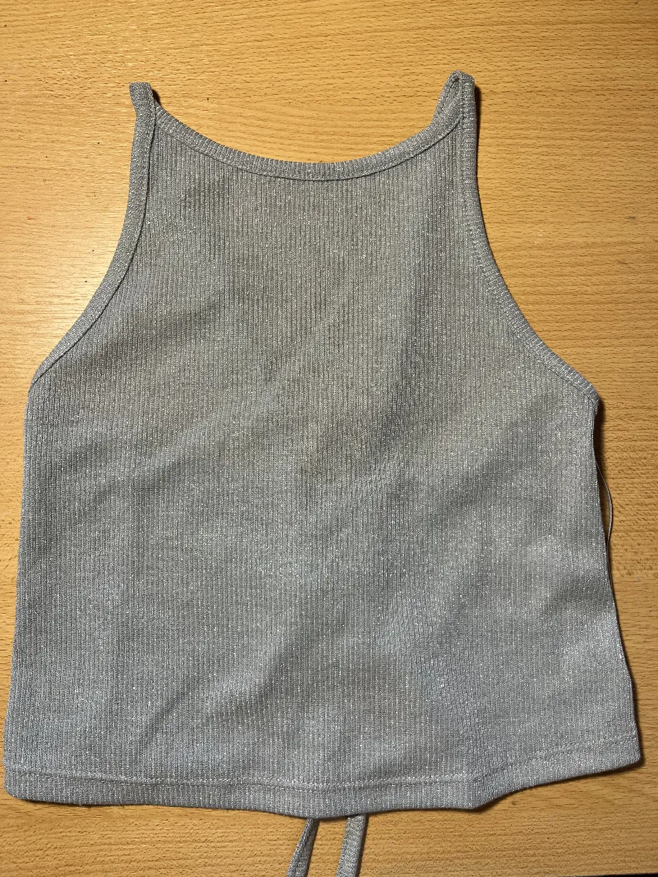 Top plateado con brillos, ideal para un look canchero y moderno. Su diseño con tiras cruzadas en la espalda le da un toque sensual y a la moda. Perfecto para combinar con jeans o faldas para salidas nocturnas o eventos especiales.