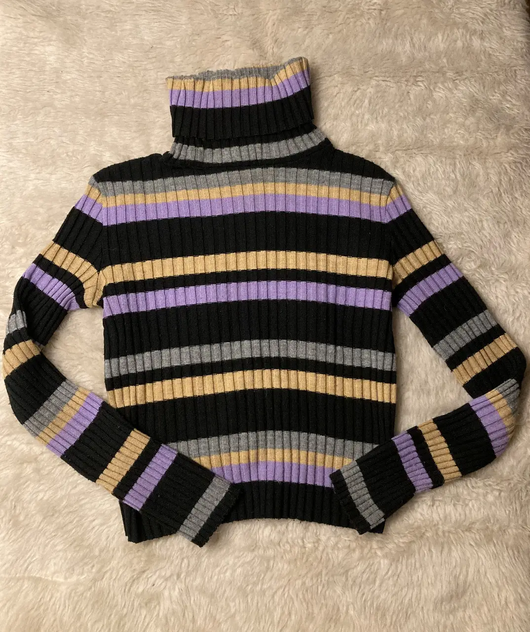 Sweater de cuello alto a rayas horizontales en negro, gris, beige y lila. Ideal para un look casual y abrigado. Es un talle 38 de la marca, equivale a un S.
