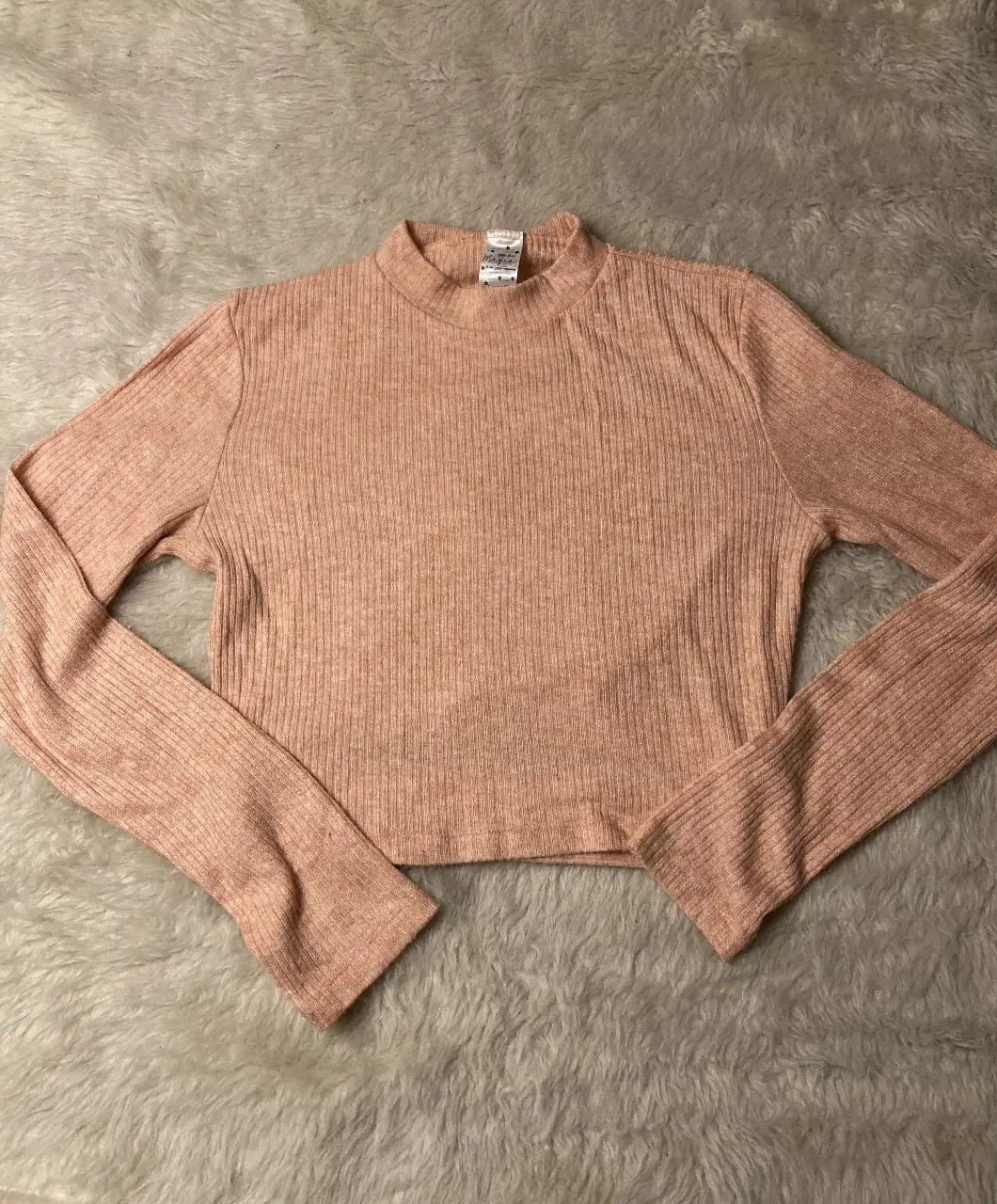 Remera manga larga tipo sweater de tejido acanalado en color rosa coral. Ideal para un look casual y cómodo. 