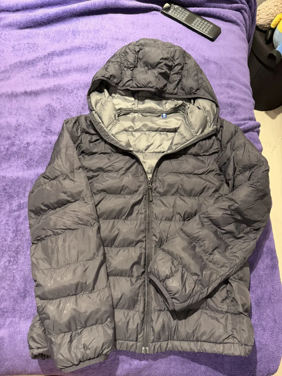 Campera gris con capucha y cierre completo. Posee bolsillos laterales y es acolchada.