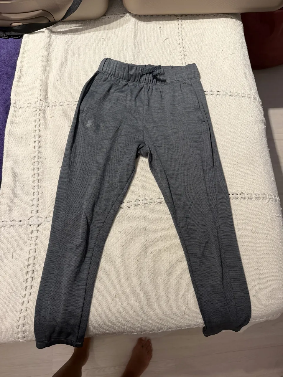 Pantalon de entrenamiento gris melange, con cordón ajustable en la cintura y logo de la marca en el frente. Ideal para entrenar o para un look casual y cómodo.