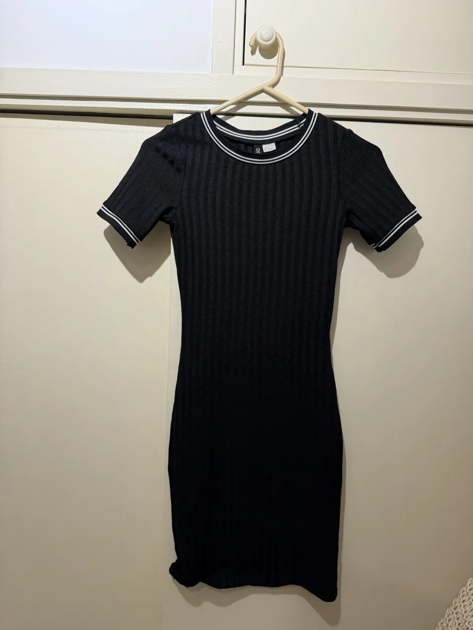 Vestido negro de H&M, estilo deportivo con detalles de rayas blancas en cuello y mangas. Ideal para un look casual y cómodo.