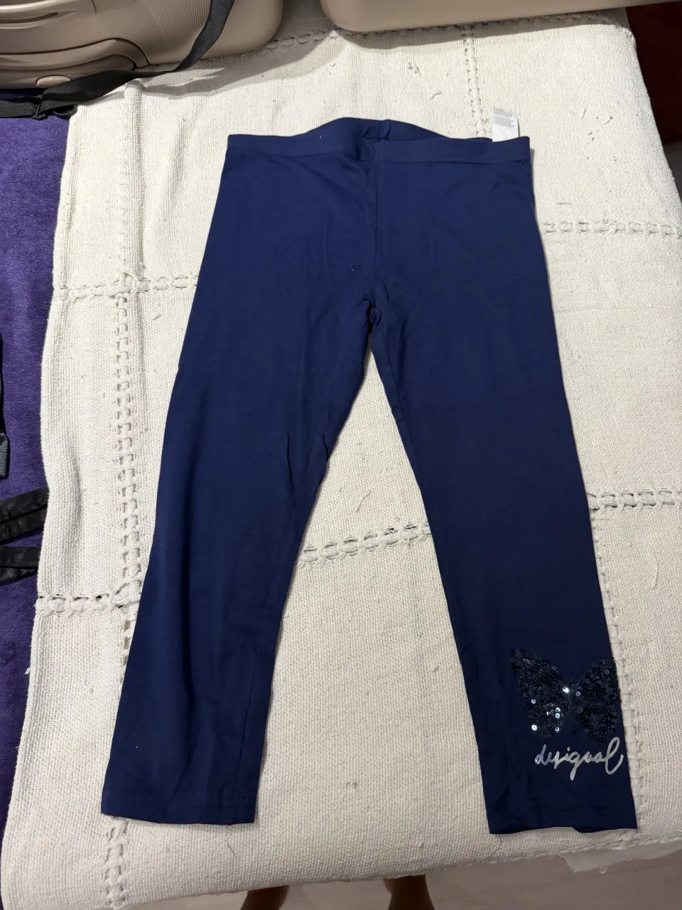 Calzas de algodón azul marino con un adorable aplique de mariposa con lentejuelas en el bajo y el logo de la marca. Perfectas para el día a día o para un look casual y divertido.