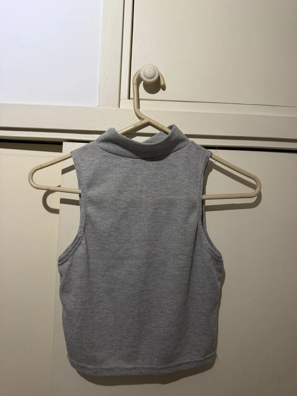 Top gris con cuello alto y detalles plateados. Ideal para un look canchero y moderno.