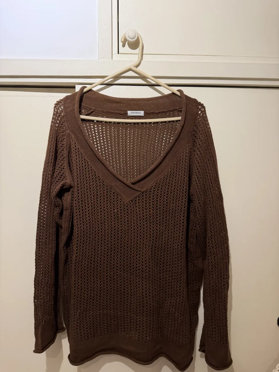 Sweater tejido de hilo color marrón, con escote en V pronunciado y detalles de rombos calados. Ideal para un look casual y cómodo.