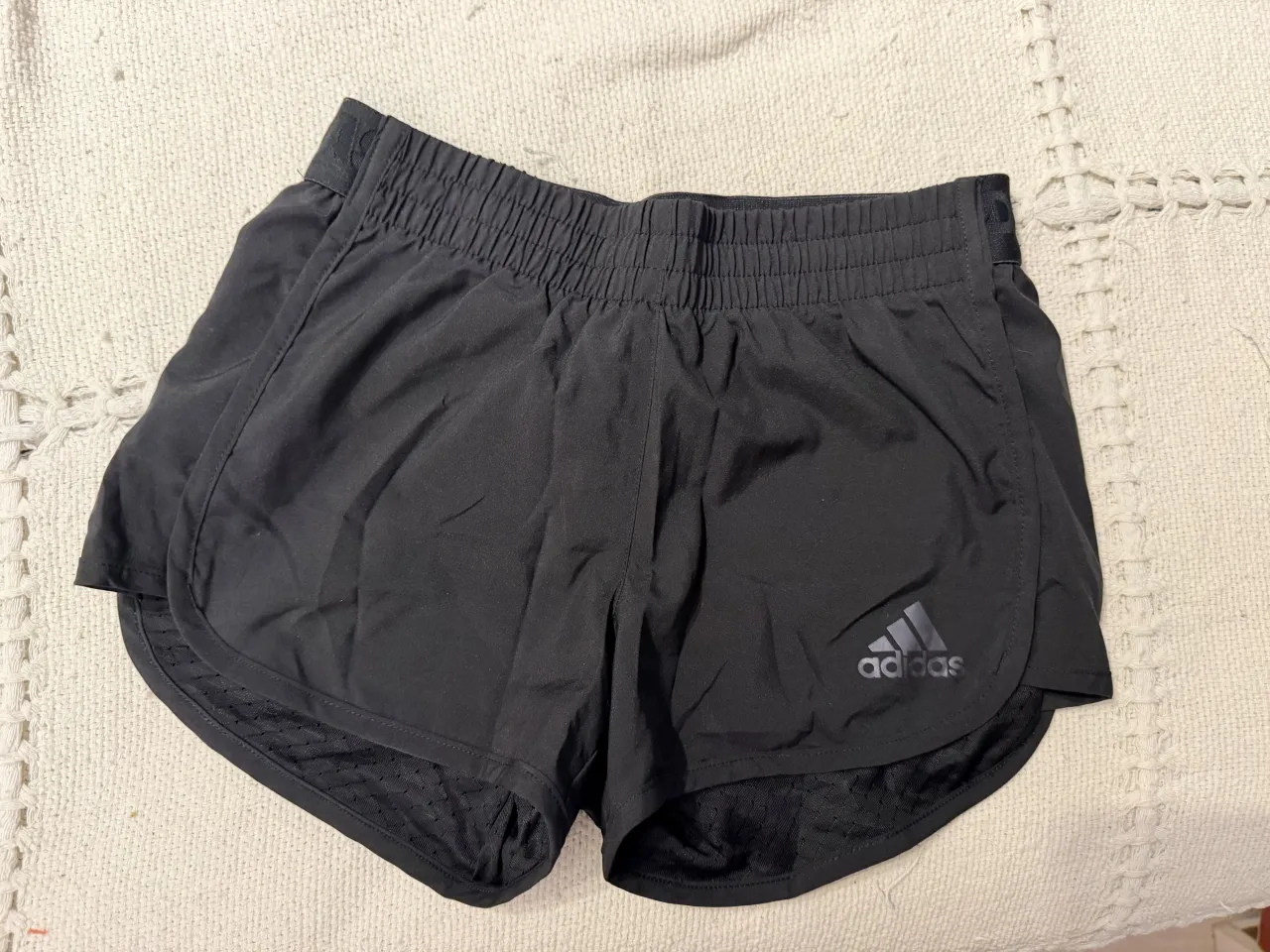 Shorts deportivos negros de Adidas con un diseño moderno y cómodo. Ideales para entrenar o para un look casual y activo. Cuentan con el logo de la marca y un detalle gráfico en la parte trasera.
