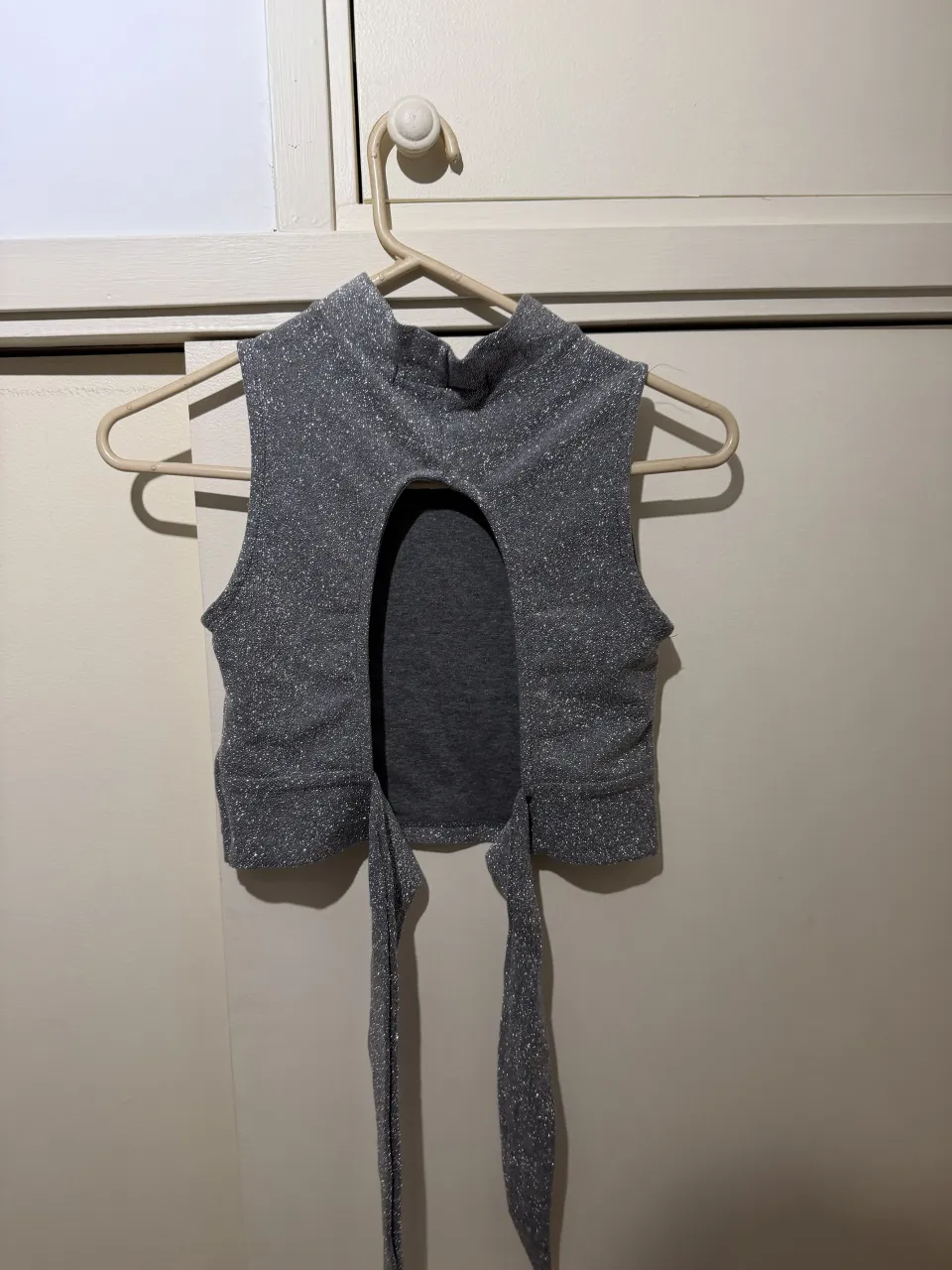 Top plateado con brillos, cuello alto y recorte delantero. Ideal para salir o una fiesta.