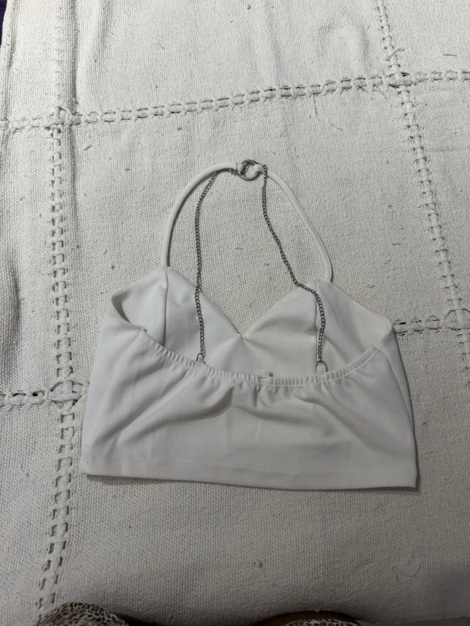 Top blanco con detalles de cadenas plateadas en la espalda y cuello. Un diseño súper canchero y moderno, ideal para combinar con jeans o faldas para un look de noche o salida.
