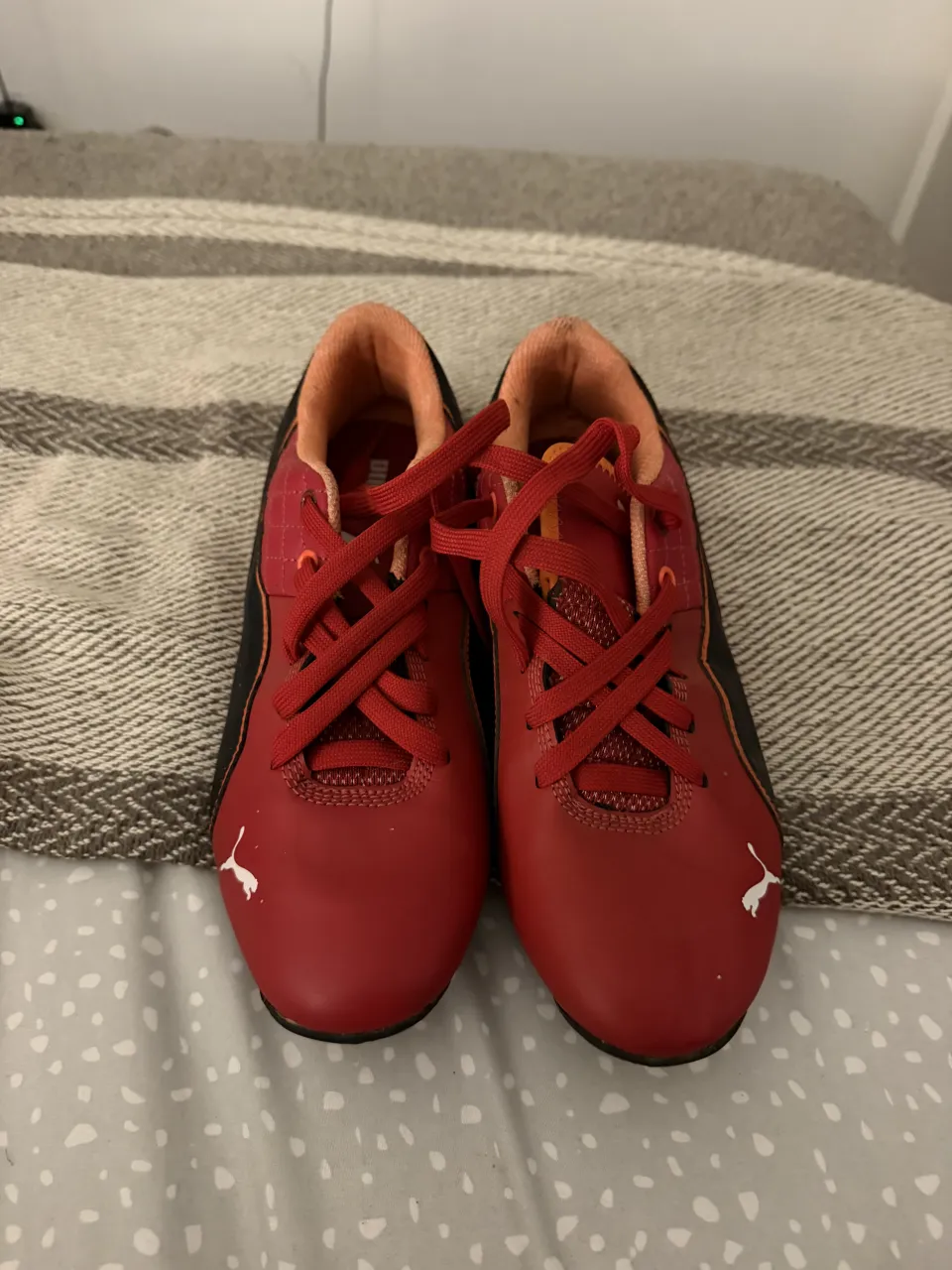 Zapatillas Puma rojas con detalles en negro y naranja. Cordones rojos.