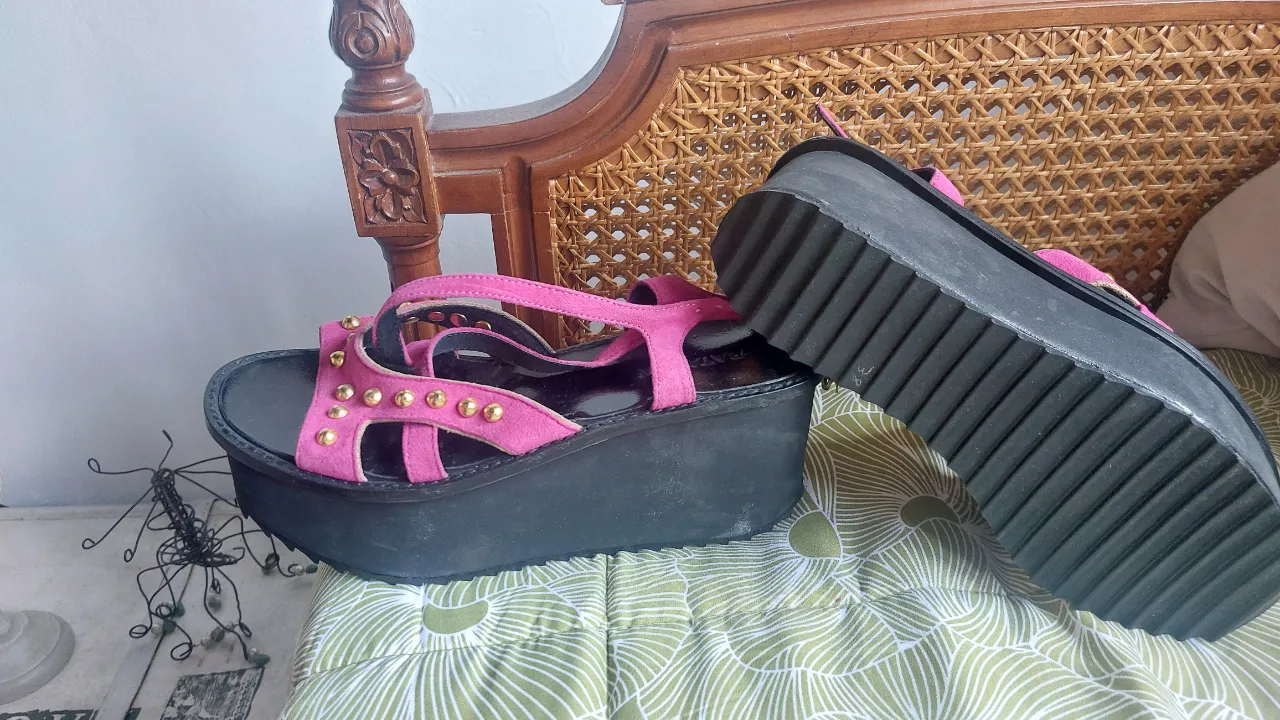 Sandalias de plataforma rosa con detalles dorados y suela negra. Ideales para un look moderno y audaz.