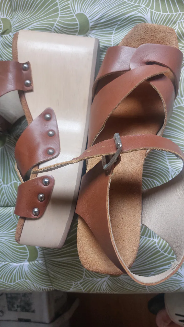 Sandalias de plataforma de madera y cuero marrón, estilo vintage. Tiras cruzadas y hebilla para ajustar.