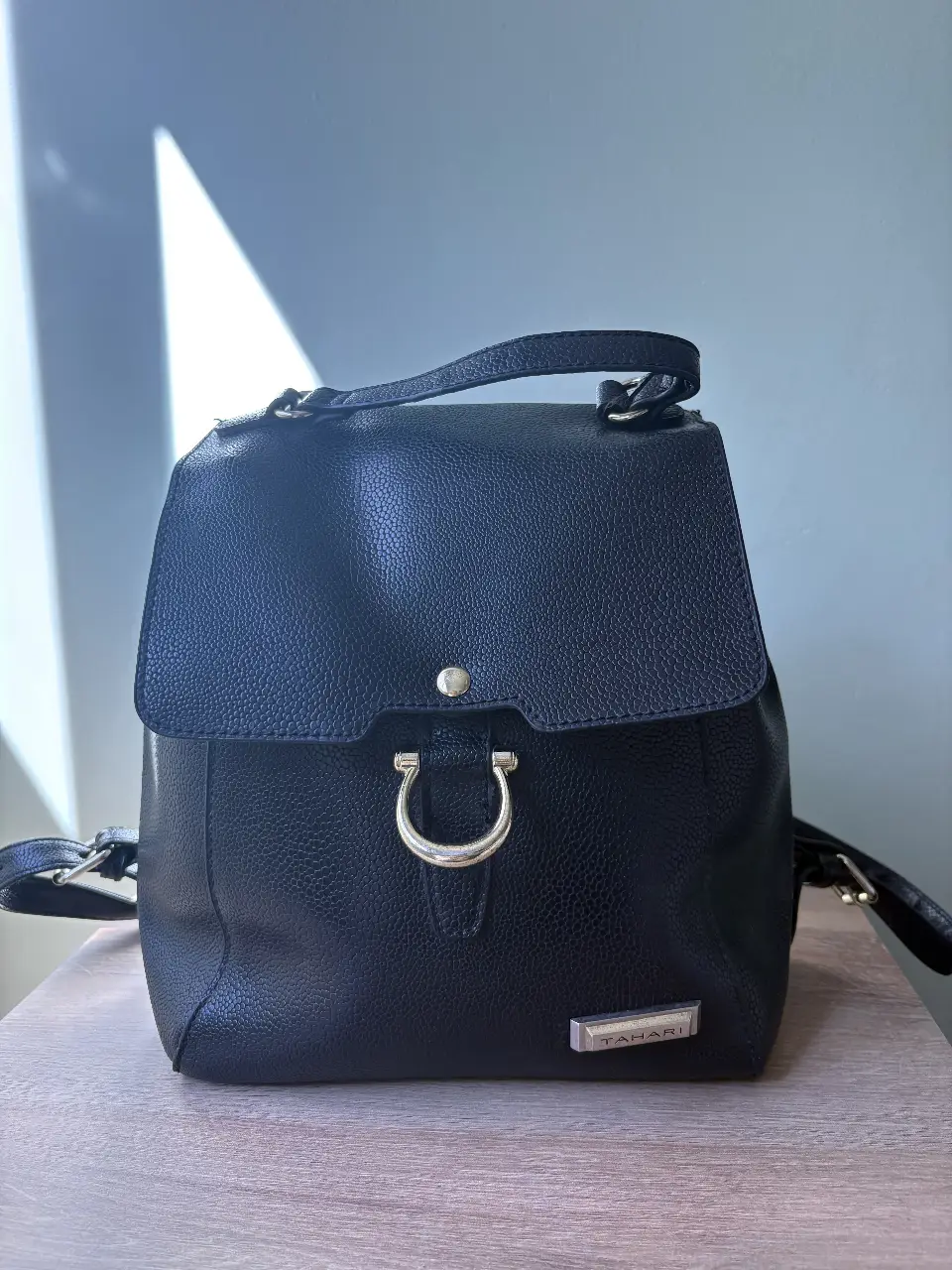 Mochila negra de cuero sintético con detalles plateados. Ideal para uso diario, con un diseño elegante y funcional. Perfecta para llevar tus esenciales con estilo.