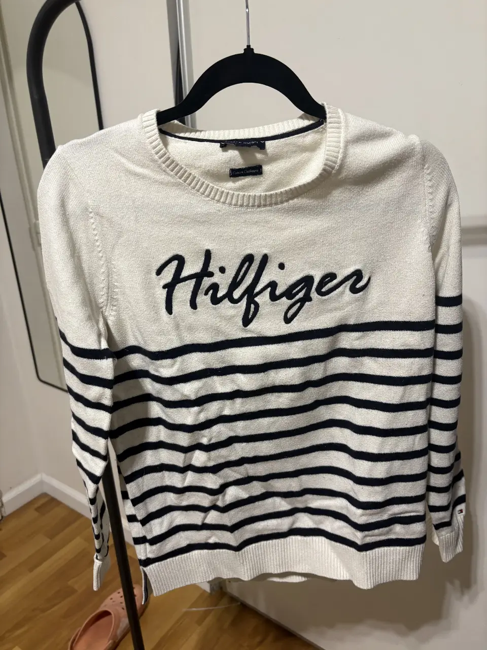 Sweater Tommy Hilfiger a rayas horizontales en blanco y azul marino. Con el logo Hilfiger bordado en el frente. Talle M.