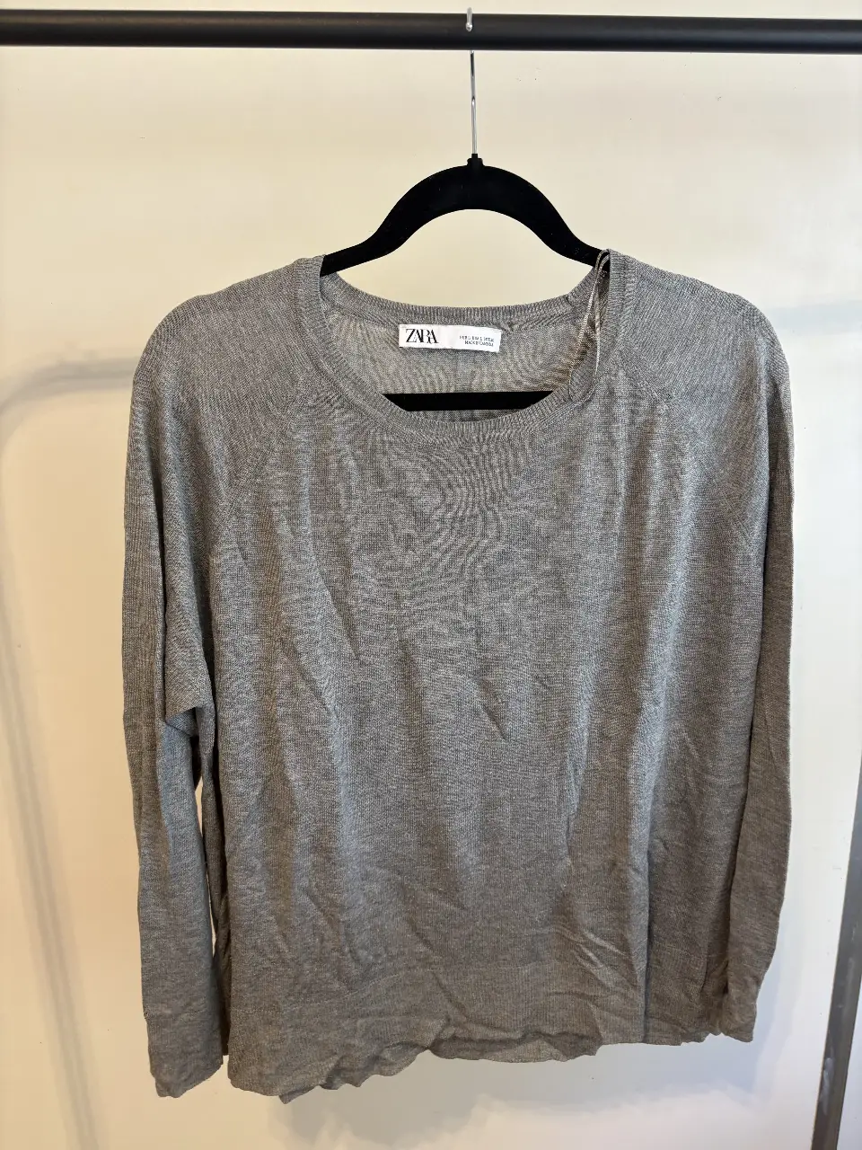 Sweater gris de la marca Zara, de manga larga y cuello redondo. Ideal para un look casual y cómodo.