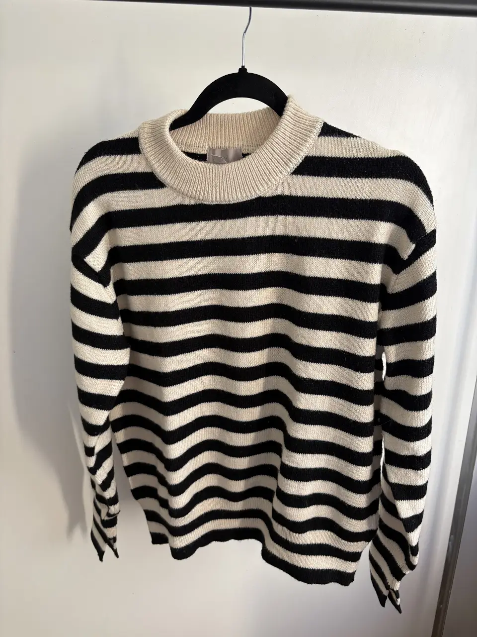 Sweater de cuello alto a rayas blanco y negro, ideal para un look casual y moderno. Perfecto para combinar con jeans o pantalones de vestir.