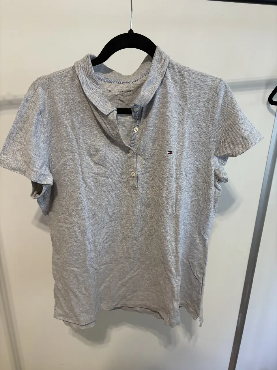 Remera Tommy Hilfiger gris, clásica, de corte regular, con cuello polo y detalle del logo bordado. Ideal para un look casual y cómodo.