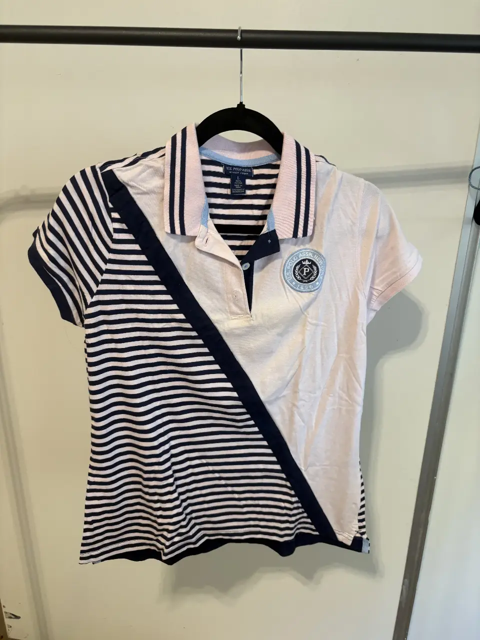 Remera polo de mujer, con diseño a rayas en azul y blanco, y detalles en rosa. Con logo de la marca en el pecho. Ideal para un look casual y deportivo.